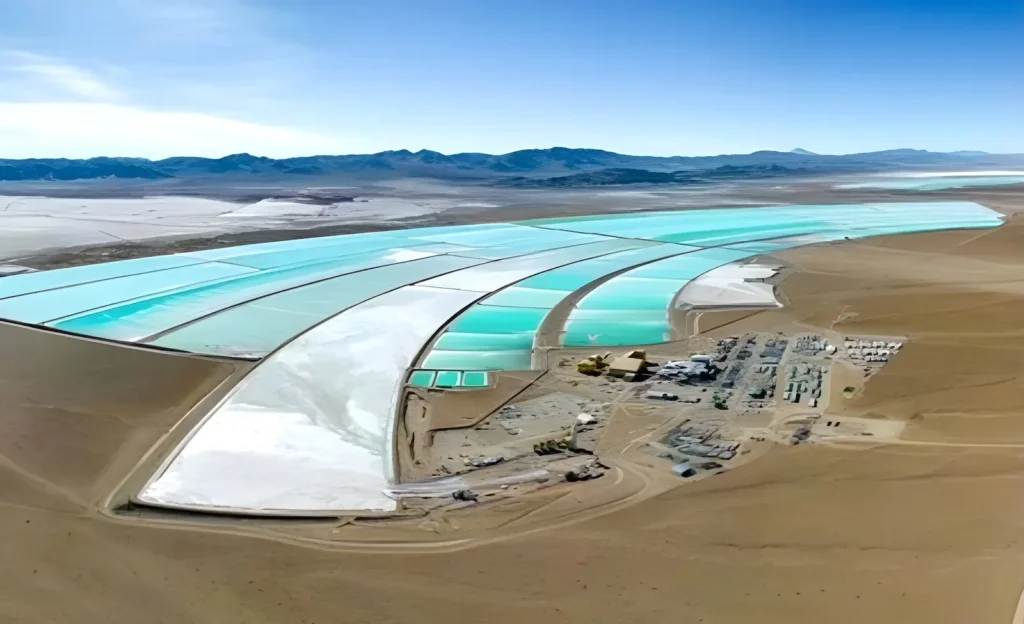 Aerial view of evaporation ponds at a lithium brine extraction site in Argentina, showcasing turquoise ponds and industrial infrastructure in a remote, arid desert landscape.